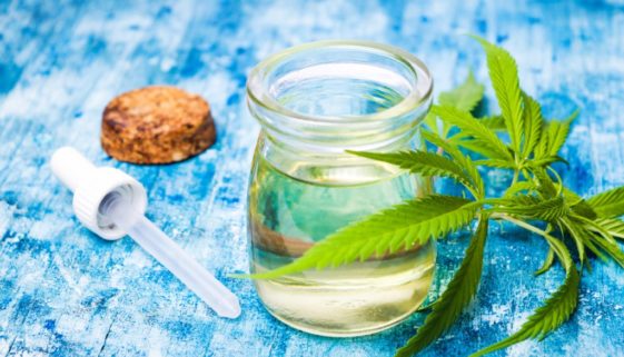 glass-container-of-hemp-cbd-oil-on-table-with-dropper-and-cannabis-leaves